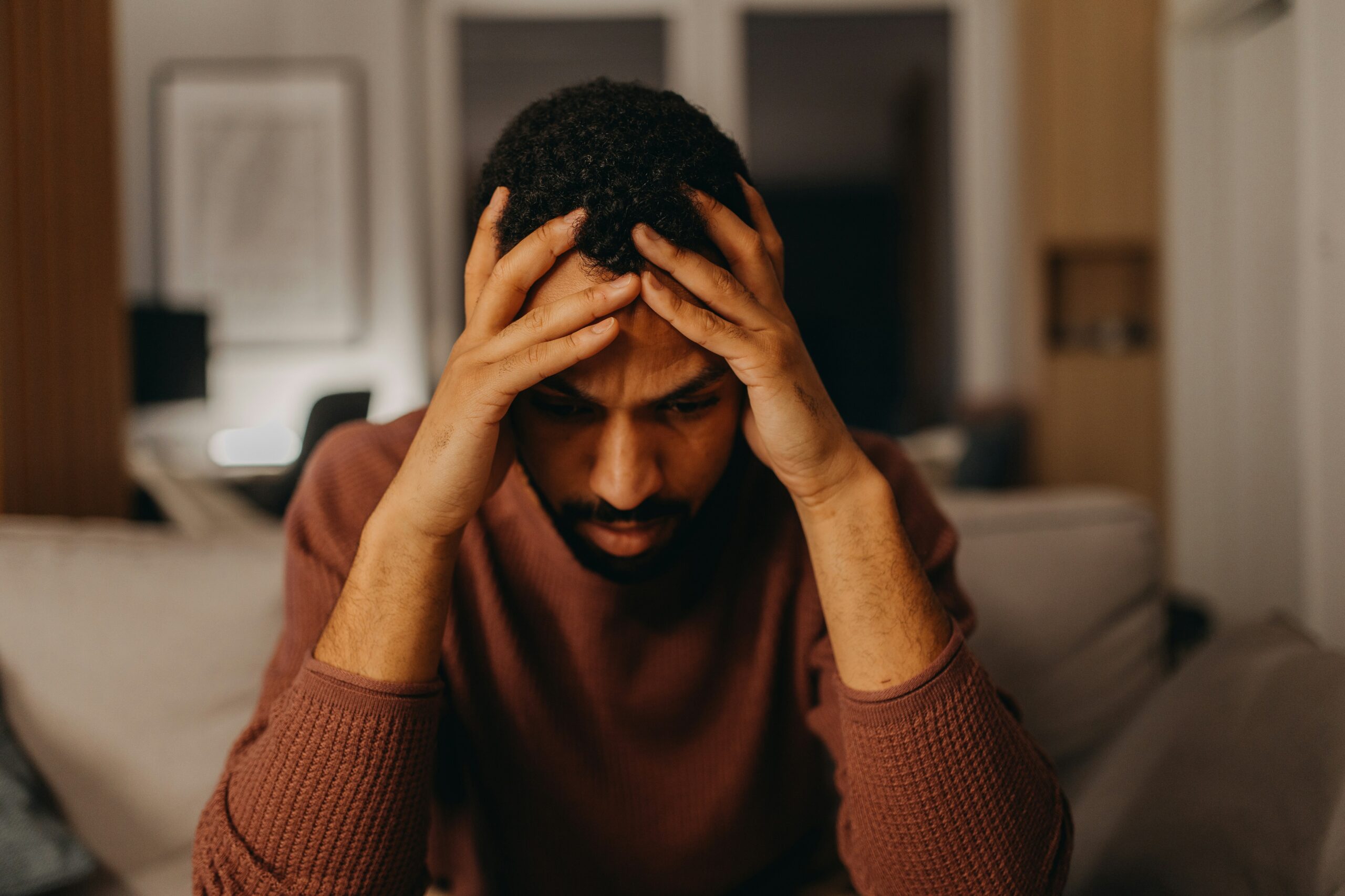 Man sitting on a couch holding his head in his hands